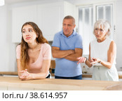 Upset adult daughter happens to reproach parents in kitchen. Стоковое фото, фотограф Яков Филимонов / Фотобанк Лори