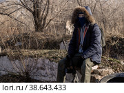 A grown man in a mask, in a jacket with a hood, in military trousers, in gloves rests in a machine gun in his hands. Стоковое фото, фотограф Владимир Арсентьев / Фотобанк Лори