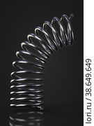 Metal spring bends against a dark background. Стоковое фото, фотограф Happyphotons / Фотобанк Лори
