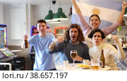 Happy sports supporters with flag of Argentina, rejoicing winning game with beer and snacks in pub. Стоковое видео, видеограф Яков Филимонов / Фотобанк Лори