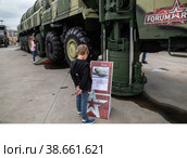 Международный военно-технический форум «Армия-2021». КВЦ Патриот Экспо. Выставка под открытым небом. Мальчик читает табличку, установленную у огромного многоосного агрегата 15У168 автономной пусковой установки "Тополь" Редакционное фото, фотограф Наталья Николаева / Фотобанк Лори