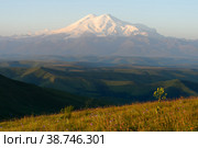 Amazing view of caucasian snow mountain or volcano Elbrus from Burmanet or Bermamyt plateau with green flower fields, blue sky background. Elbrus landscape view - the highest peak of Russia and Europe. Стоковое фото, фотограф Евгений / Фотобанк Лори