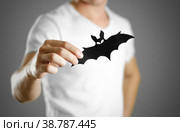 A man in a white t-shirt holds a black silhouette of a bat. Close up. Стоковое фото, фотограф Плотников Дмитрий / Фотобанк Лори