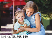 older sister tickles younger sister on the veranda in the park. Стоковое фото, фотограф Поликарпов Владимир Владимирович / Фотобанк Лори