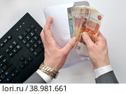 Концепт коррупции. Взятка. Чиновник пересчитывает деньги в конверте. Стоковое фото, фотограф Александр Тарасенков / Фотобанк Лори