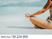 Crop of female hands and legs meditating activity on the beach. Стоковое фото, фотограф Igor Tichonow / Фотобанк Лори