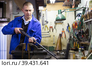 Confident gunsmith lubricates and cleans barrel of rifled shotgun. Стоковое фото, фотограф Яков Филимонов / Фотобанк Лори