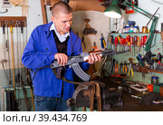 Gunsmith with Kalashnikov assault rifle in weapons workshop. Стоковое фото, фотограф Яков Филимонов / Фотобанк Лори
