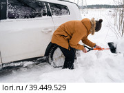 A man digs out a stalled car in the snow with a car shovel. Transport in winter got stuck in a snowdrift after a snowfall, sat on the bottom. First aid, tow truck, winter tires spikes and all-season. Стоковое фото, фотограф Ольга Симонова / Фотобанк Лори