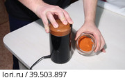 A man pours dried red pepper into a coffee grinder for grinding. Grinding hot pepper. Medium plan. Стоковое видео, видеограф Vadzim Yakubovich / Фотобанк Лори