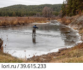 Южный Урал осенью, рыбак ставит сеть на льду реки Белой. Southern Urals in autumn, a fisherman puts a net on the ice of the Belaya River. (2022 год). Редакционное фото, фотограф Евгений Романов / Фотобанк Лори