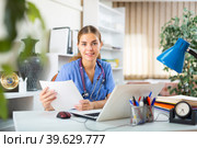 Smiling young woman therapist filling up medical forms on laptop in office. Стоковое фото, фотограф Яков Филимонов / Фотобанк Лори
