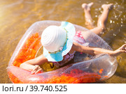 Girl in a hat swimming in the river with a transparent inflatable circle in the shape of a heart with orange feathers inside.The sea with a sandy bottom. Beach holidays, swimming, tanning, sunscreens. Стоковое фото, фотограф Ольга Симонова / Фотобанк Лори