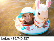 Girl in a hat swimming in the river with inflatable circle in the shape of a lama. Inflatable alpaca for a child. Sea with a sandy bottom. Beach holidays, swimming, tanning, sunscreens. Стоковое фото, фотограф Ольга Симонова / Фотобанк Лори