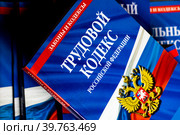Брошюра с Трудовым кодексом Российской Федерации лежит на столе в офисе сотрудника отдела кадров (2023 год). Редакционное фото, фотограф Николай Винокуров / Фотобанк Лори