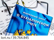 Федеральный закон Российской Федерации "О бухгалтерском учете" лежит на столе у бухгалтера (2023 год). Редакционное фото, фотограф Николай Винокуров / Фотобанк Лори