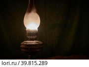 Rusty, old, cobwebbed and dusty kerosene lamp prepared for Halloween. A bright fire burns through the smoky, dusty glass. Dark rag background. Selective focus. Стоковое фото, фотограф Andrey Tishakov / Фотобанк Лори