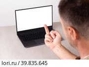 A man shows an indecent gesture fuck you to the laptop screen with a white mockup on the monitor with clipping path, selective focus. Стоковое фото, фотограф Андрей С / Фотобанк Лори