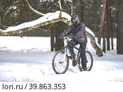 Winter sports. Cycling trips. A young man in black clothes rides a bicycle. Стоковое фото, фотограф Кутина Татьяна / Фотобанк Лори