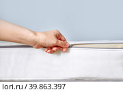 Orthopedic mattress with removable cover. Hand unzips the zipper close-up. Copy space. Стоковое фото, фотограф Кутина Татьяна / Фотобанк Лори