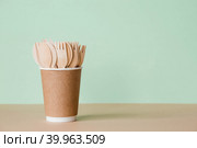Экологически чистая одноразовая кухонная утварь в бумажном стаканчике на бежево-зеленом фоне. Деревянные вилки, ложки и ножи. Экология, концепция нулевых отходов. Стоковое фото, фотограф Photojuli / Фотобанк Лори