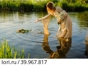 Девушка в традиционной русской одежде опускает венок на воду. Стоковое фото, фотограф Сергей Буторин / Фотобанк Лори