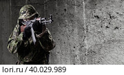 An armed soldier in military uniform aims with a rifle. One, against the backdrop of a concrete gray wall. Стоковое фото, фотограф Владимир Арсентьев / Фотобанк Лори