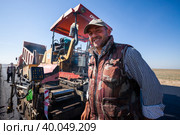 Kyzylorda province, Kazakhstan, April 29, 2012: Construction of West Europe-West China new highway. Smiling worker against Dynapac road machine and dump truck. Стоковое фото, фотограф Alexey Rezvykh / Фотобанк Лори