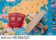 Туризм. Модель старинного самолета air и российский паспорт на фоне карты мира. Концепция путешествий, приключений и открытий. (2023 год). Стоковое фото, фотограф Photojuli / Фотобанк Лори