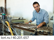 Farmer man working with automatic filling and seeding line for growing containerized seedlings of decorative plants in greenhouse. Стоковое фото, фотограф Яков Филимонов / Фотобанк Лори