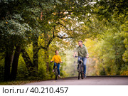 Happy father and daughter ride bicycles in autumn park on sunny day. Стоковое фото, фотограф Мария Мороз / Фотобанк Лори