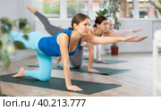 Women of different ages performing Balancing Table restorative Pose or Dandayamana Bharmanasana during yoga training together in studio. Стоковое фото, фотограф Яков Филимонов / Фотобанк Лори