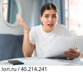 Upset woman with financial documents sitting at the table. Стоковое фото, фотограф Яков Филимонов / Фотобанк Лори
