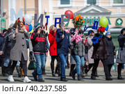 Дети и подростки идут по улице во время первомайской демонстрации. Демонстранты несут большие буквы. Текст на русском языке: "Мир, Труд". Праздник Весны и Труда. Город Магадан, Магаданская область, Россия. Редакционное фото, фотограф Андрей Степанов / Фотобанк Лори
