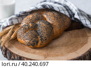 Классическая пшеничная коса или плетёнка с маком. Вкусный хлеб крупным планом. Свежеиспеченный хлеб на закваске с золотистой корочкой на деревянной доске. Контекст пекарни с вкусным хлебом. Кондитерские изделия. Стоковое фото, фотограф Photojuli / Фотобанк Лори
