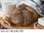 Классическая пшеничная коса или плетёнка с маком. Вкусный хлеб крупным планом. Свежеиспеченный хлеб на закваске с золотистой корочкой на деревянной доске. Контекст пекарни с вкусным хлебом. Кондитерские изделия. Стоковое фото, фотограф Photojuli / Фотобанк Лори