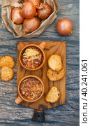 Two servings of traditional French onion soup with baguette and gruyere cheese (emmental, comte or beaufort) in ceramic bowls on a wooden background. Selective focus. Стоковое фото, фотограф Виктория Панченко / Фотобанк Лори