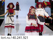Девушки демонстрируют Удмутрский национальный костюм на подиуме в рамках шоу "Грани Мира" на фестивале детской моды Kids Fashion Week в "Центральном детском магазине на Лубянке" (ЦДМ) в Москве, Россия (2023 год). Редакционное фото, фотограф Николай Винокуров / Фотобанк Лори