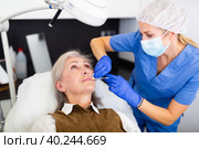 Cosmetologist making injections of botulotoxin in face of mature woman. Стоковое фото, фотограф Яков Филимонов / Фотобанк Лори