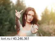 Selective focus of jewish woman model showing middle fingers at camera, fuck you sign, looking at camera. Young cute brunette lady impolite and rude fuck off expression, outdoors. Copy ad text space. Стоковое фото, фотограф Aleksandr Golubev / Фотобанк Лори