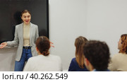 Experienced female teacher giving lecture to group of student Knowledgeable female professor explaining subject to classroom full of students Competent female tutor teaching students in college. Стоковое видео, видеограф Яков Филимонов / Фотобанк Лори