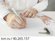 Мужчина, заполняющий документ, с лежащими на столе ключами и деньгами. A person without a face signs a deed of gift, power of attorney, testament on a blank form. Nearby are the keys to the apartment and banknotes of Russian money. Стоковое фото, фотограф Валерий Елистратов / Фотобанк Лори