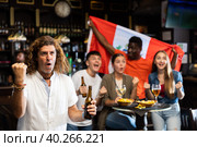 Cheerful diverse football supporters holding the flag of Peru and enjoing beer chips in the sport bar. Стоковое фото, фотограф Яков Филимонов / Фотобанк Лори