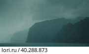 Gloomy ocean landscape with gray storm clouds. Fog covered high sea cliffs on shore. Mystical foggy haze inspires fear and greatness. Стоковое видео, видеограф Ольга Сухарева / Фотобанк Лори