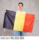 Joyous young woman holding Belgium flag against unicoloured background. Стоковое фото, фотограф Яков Филимонов / Фотобанк Лори