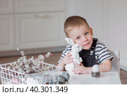 A little boy and a white Easter bunny. We are preparing the family for a Bright Easter. A child is playing with eggs. Стоковое фото, фотограф Photojuli / Фотобанк Лори