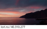 Dramatic cloudscape at sunset with reflection on ocean surface of pink clouds sky. Scenic viewpoint on sea water waves. Steep cliff bluff, Tenerife coast, Spain. Стоковое видео, видеограф Ольга Сухарева / Фотобанк Лори