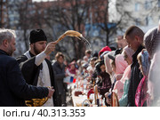 Russia, the City of Vidnoye, April 15, 2023. Easter service. The priest sprinkles people and Easter treats with holy water at the entrance to the temple. People go to sanctify eggs and cakes. Редакционное фото, фотограф Photojuli / Фотобанк Лори