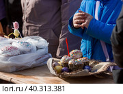 Russia, the City of Vidnoye, April 15, 2023. Easter service. The priest sprinkles people and Easter treats with holy water at the entrance to the temple. People go to sanctify eggs and cakes. Редакционное фото, фотограф Photojuli / Фотобанк Лори