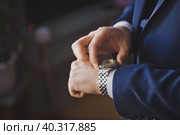 The groom looks at the time on a hand watch 2616. Стоковое фото, фотограф Алёна Замотаева / Фотобанк Лори